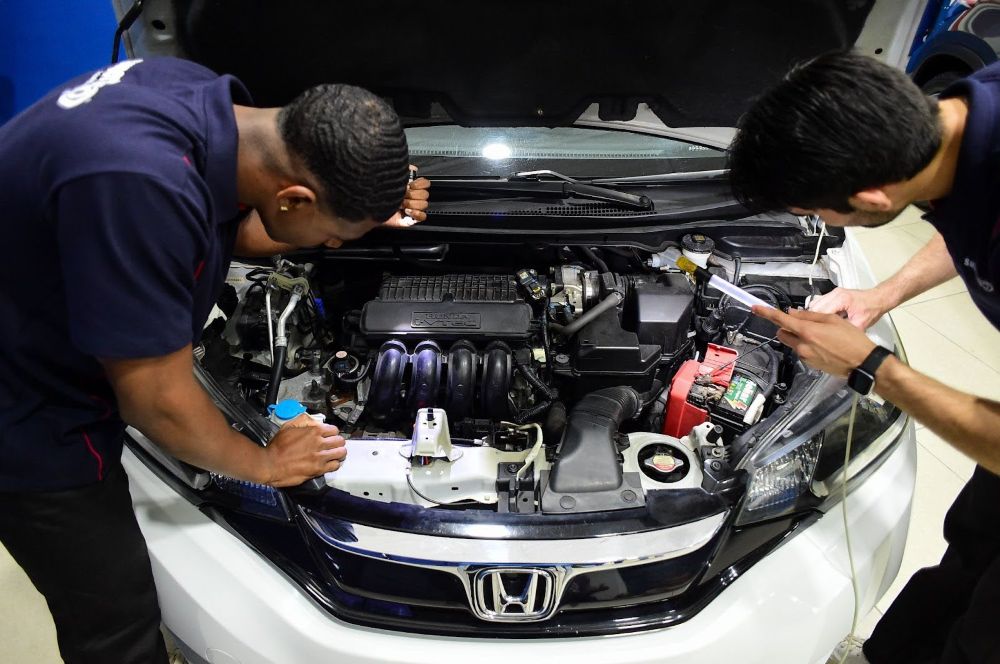 Profissional realiza vistoria cautelar em veículo, inspecionando etiqueta sob o tapete com lanterna para garantir autenticidade e segurança.