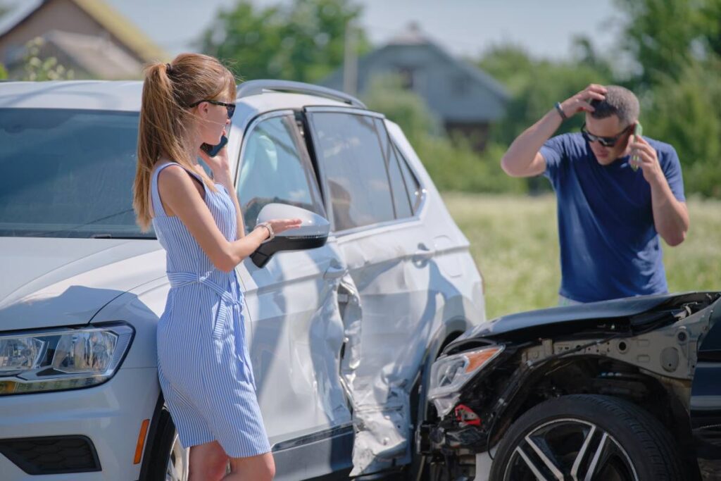 um homem e uma mulher ao lado de dois carros que colidiram.