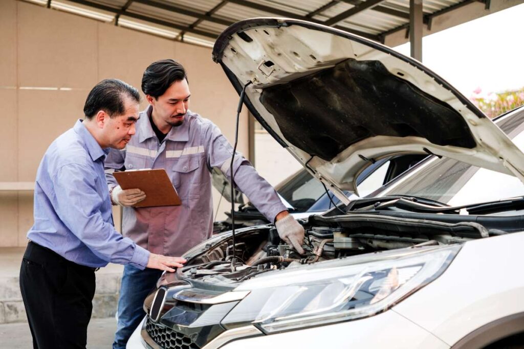 dois homens examinando o motor de um carro.