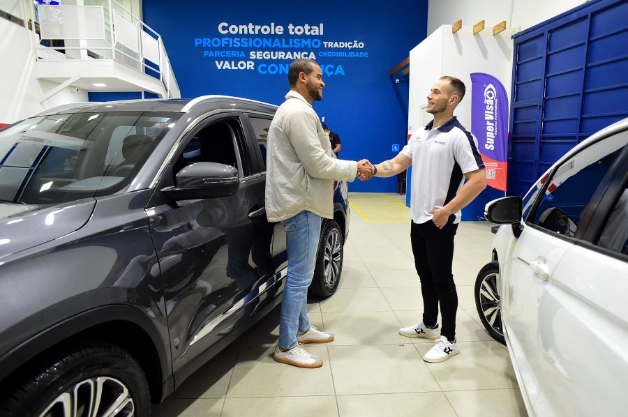 Dois homens apertando mãos após serviço de vistoria automotiva.