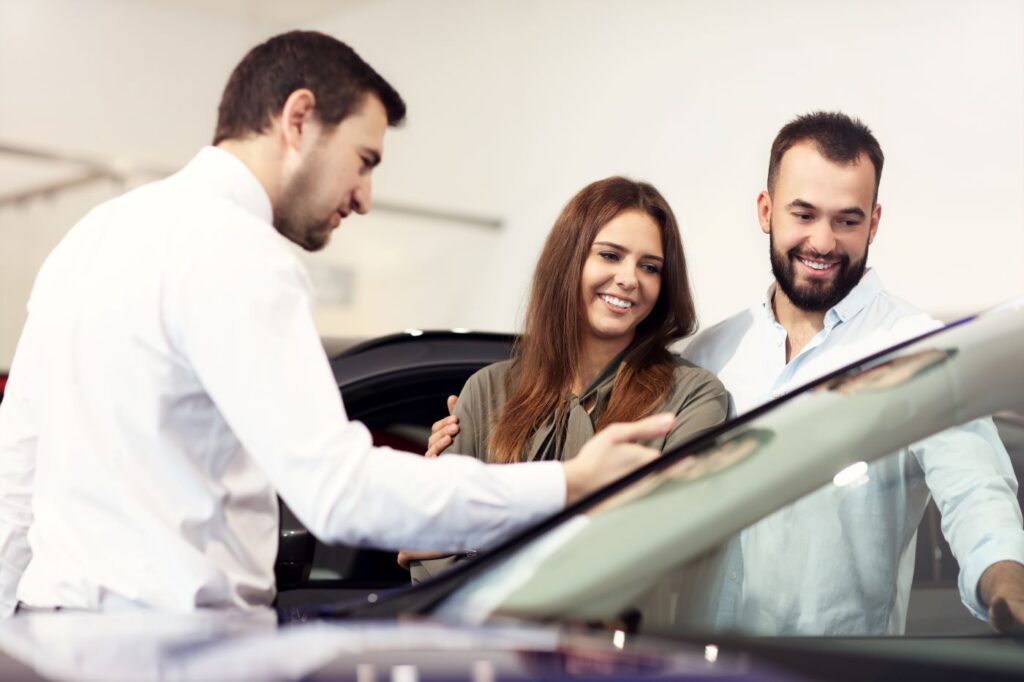 Casal de homem e mulher avaliando carro com vendedor após descobrirem como financiar um carro