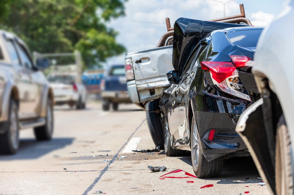 Carro com a traseira destruída após colisão, sugerindo dano estrutural na longarina.