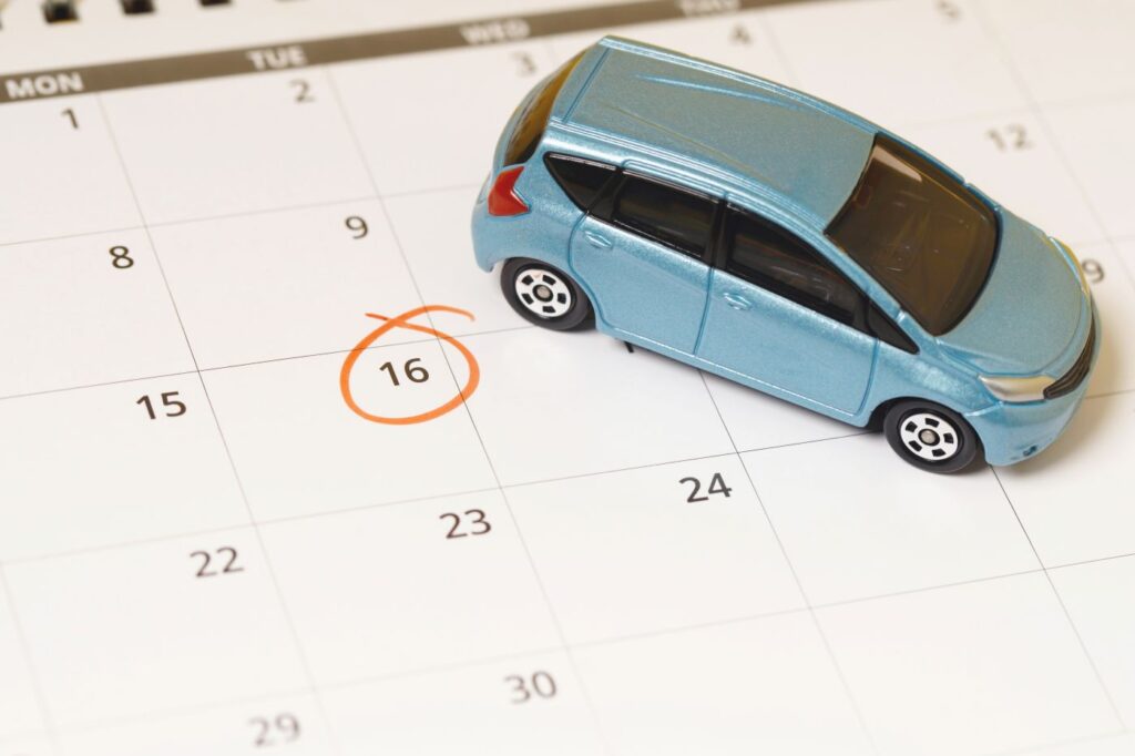 Carro em miniatura em cima de calendário de papel com data circulada para indicar prazos e calendário de licenciamento 2025