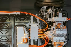 Vista interna de um veículo elétrico com componentes e cabos laranja de alta voltagem, exibindo o sistema de tração e a parte mecânica detalhada. carros chineses no brasil